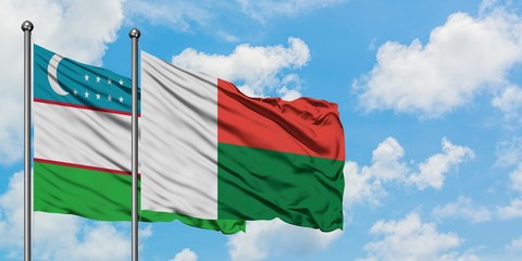 Uzbekistan and Madagascar flag waving in the wind against white cloudy blue sky together. Diplomacy concept, international relations.