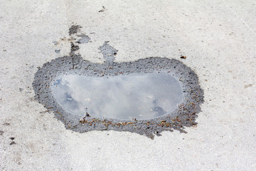 apple-shaped puddle on the pavement