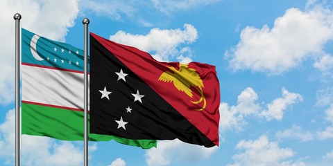 Uzbekistan and Papua New Guinea flag waving in the wind against white cloudy blue sky together. Diplomacy concept, international relations.