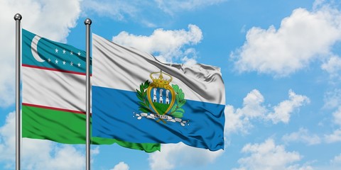 Uzbekistan and San Marino flag waving in the wind against white cloudy blue sky together. Diplomacy...
