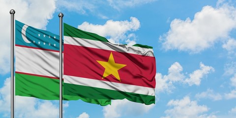 Uzbekistan and Suriname flag waving in the wind against white cloudy blue sky together. Diplomacy concept, international relations.