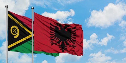 Vanuatu and Albania flag waving in the wind against white cloudy blue sky together. Diplomacy...