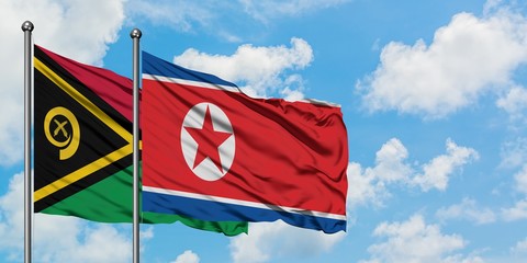 Vanuatu and North Korea flag waving in the wind against white cloudy blue sky together. Diplomacy...