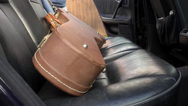 Slow Motion Close POV Shot Of A Man Placing An Electric Guitar In Its Case On The Back Seat Of A Car, Then Closing The Door.