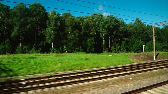 High-speed Train fast moves past a forest and a railway in the day
