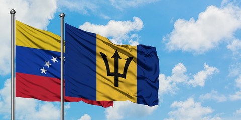 Venezuela and Barbados flag waving in the wind against white cloudy blue sky together. Diplomacy...