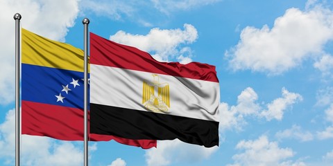 Venezuela and Egypt flag waving in the wind against white cloudy blue sky together. Diplomacy concept, international relations.
