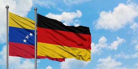 Venezuela and Germany flag waving in the wind against white cloudy blue sky together. Diplomacy concept, international relations.
