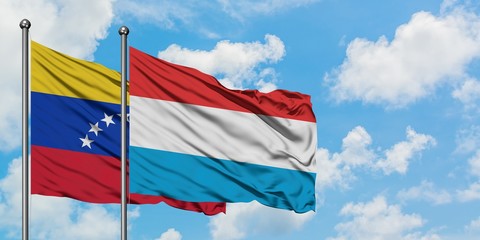 Venezuela and Luxembourg flag waving in the wind against white cloudy blue sky together. Diplomacy concept, international relations.