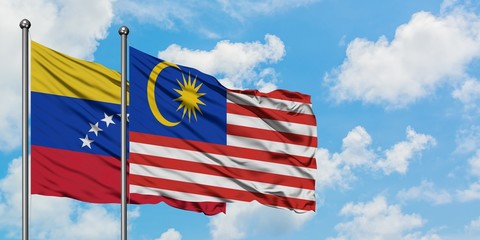 Venezuela and Malaysia flag waving in the wind against white cloudy blue sky together. Diplomacy concept, international relations.