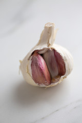 Garlic bulb split open on marble background with copy space