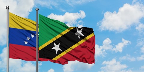Venezuela and Saint Kitts And Nevis flag waving in the wind against white cloudy blue sky together. Diplomacy concept, international relations.