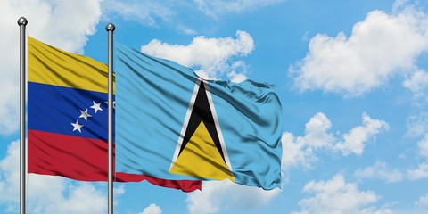 Venezuela and Saint Lucia flag waving in the wind against white cloudy blue sky together. Diplomacy...
