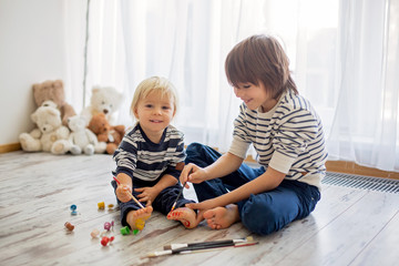 Obraz premium Brothers, playing at home, painting on their feet, tickling, laughing, smiling