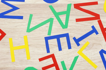 colorful jumbled letters, made of paper,  lying on wood