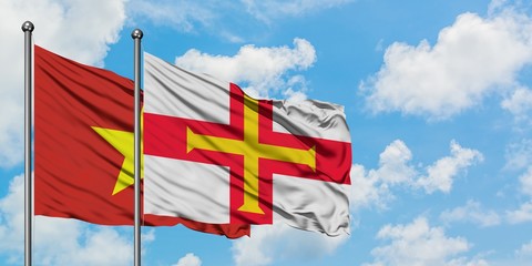 Vietnam and Guernsey flag waving in the wind against white cloudy blue sky together. Diplomacy concept, international relations.