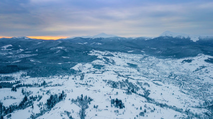Fototapeta na wymiar amazing winter landscape. mountains covered with snow and blue cloudy sky. drone shot, bird's eye