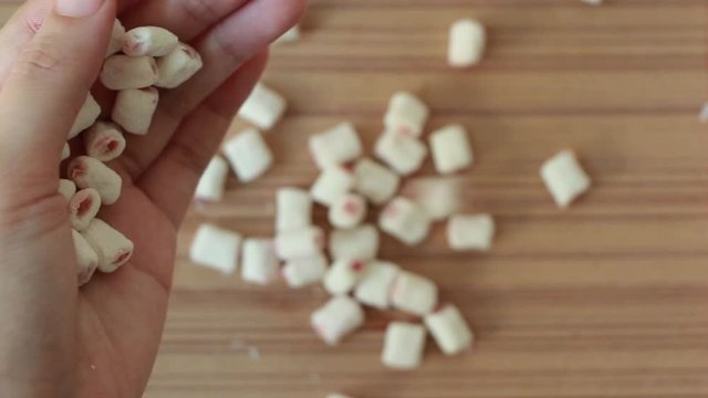 ็Hand putting marshmallow on wood tray.