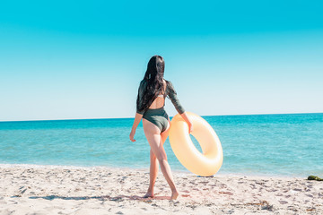 Portrait of a girl in pink glasses and with an orange rubber ring on the beach.