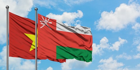 Vietnam and Oman flag waving in the wind against white cloudy blue sky together. Diplomacy concept, international relations.