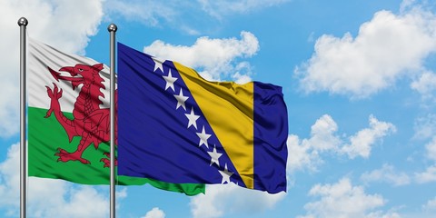 Wales and Bosnia Herzegovina flag waving in the wind against white cloudy blue sky together. Diplomacy concept, international relations.