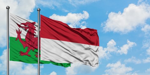 Wales and Indonesia flag waving in the wind against white cloudy blue sky together. Diplomacy concept, international relations.