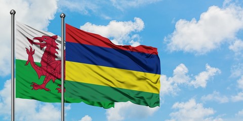 Wales and Mauritius flag waving in the wind against white cloudy blue sky together. Diplomacy concept, international relations.