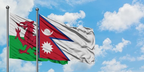 Wales and Nepal flag waving in the wind against white cloudy blue sky together. Diplomacy concept, international relations.