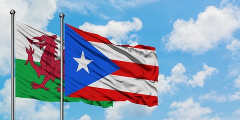 Wales and Puerto Rico flag waving in the wind against white cloudy blue sky together. Diplomacy concept, international relations.