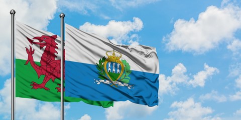 Wales and San Marino flag waving in the wind against white cloudy blue sky together. Diplomacy...