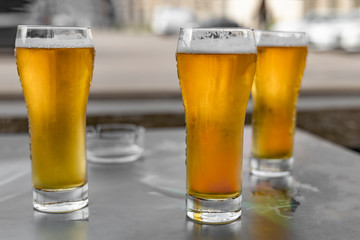 Three glasses of light beer close-up. Outdoor cafe.