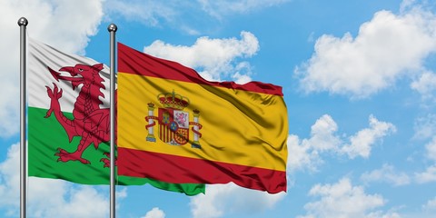 Wales and Spain flag waving in the wind against white cloudy blue sky together. Diplomacy concept, international relations.