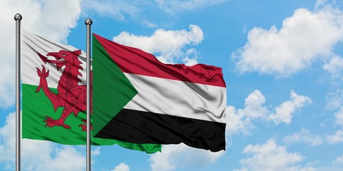 Wales and Sudan flag waving in the wind against white cloudy blue sky together. Diplomacy concept, international relations.
