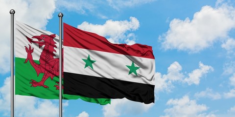 Wales and Syria flag waving in the wind against white cloudy blue sky together. Diplomacy concept, international relations.