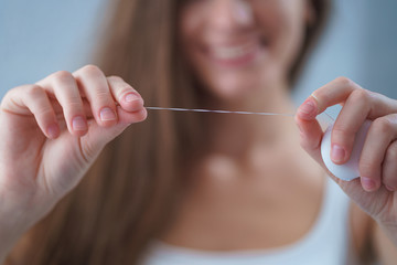 Happy healthy woman uses dental floss for brushing teeth and oral hygiene at home. Teeth oral care
