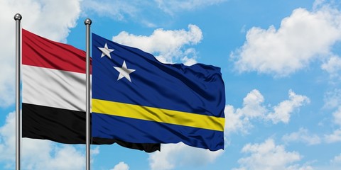 Yemen and Curacao flag waving in the wind against white cloudy blue sky together. Diplomacy concept, international relations.