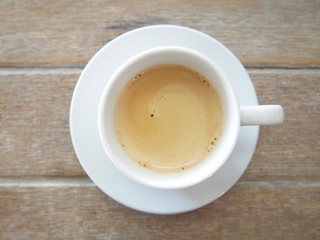 Espresso coffee in a white mug placed on a wooden floor.