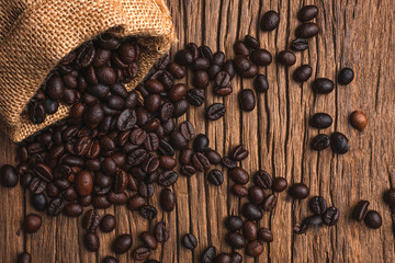 Coffee beans in bag on a old wooden background,Close up roasted coffee beans in small sack on wooden table. Outdoor shooting with sunlight and blur background