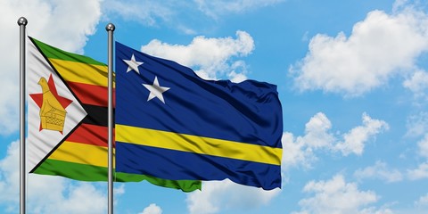 Zimbabwe and Curacao flag waving in the wind against white cloudy blue sky together. Diplomacy concept, international relations.