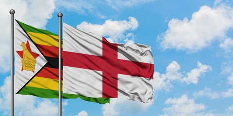 Zimbabwe and England flag waving in the wind against white cloudy blue sky together. Diplomacy concept, international relations.