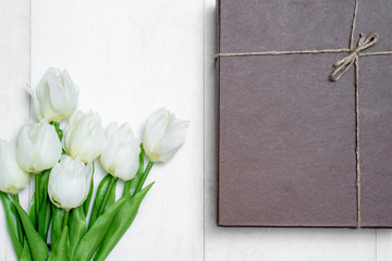 Spring tulip flowers and paper card on gray stone table from above in flat lay style. Greeting for Women's or Mothers Day
