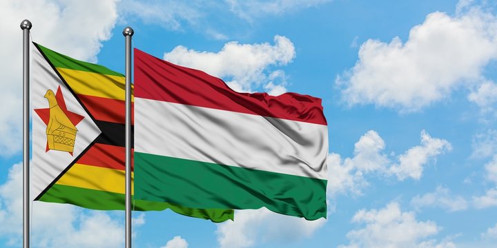 Zimbabwe and Hungary flag waving in the wind against white cloudy blue sky together. Diplomacy concept, international relations.