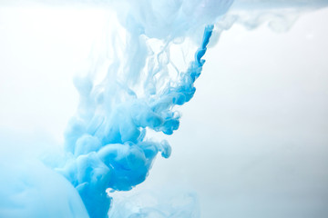 Abstract flowing liquid or blue ink in water on a white background. It looks like smoke or cloud....