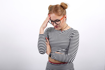 Pretty young blonde woman wearing nice striped shirt and glasses over white background, looking funny, thinking about issue, laughing