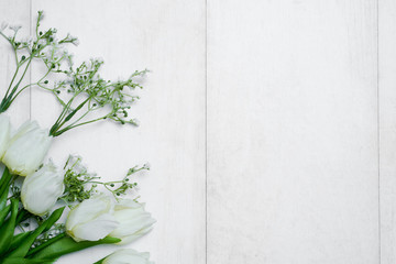 Spring tulip flowers and paper card on gray stone table from above in flat lay style. Greeting for Women's or Mothers Day