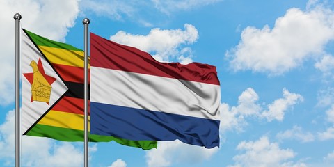 Zimbabwe and Netherlands flag waving in the wind against white cloudy blue sky together. Diplomacy concept, international relations.