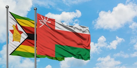 Zimbabwe and Oman flag waving in the wind against white cloudy blue sky together. Diplomacy concept, international relations.