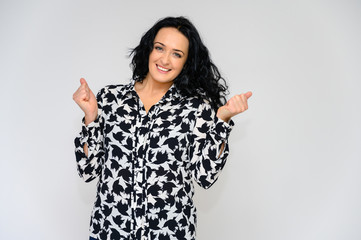 Portrait of a pretty brunette woman with long curly hair on a white background in a black and white blouse. He stands in front of the camera, smiles, talks in various poses.