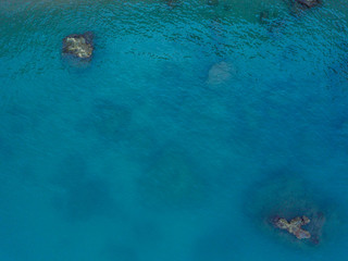 Aerial view of tranquil sea surface with stones and rocks in water.