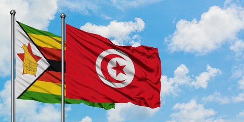 Zimbabwe and Tunisia flag waving in the wind against white cloudy blue sky together. Diplomacy concept, international relations.